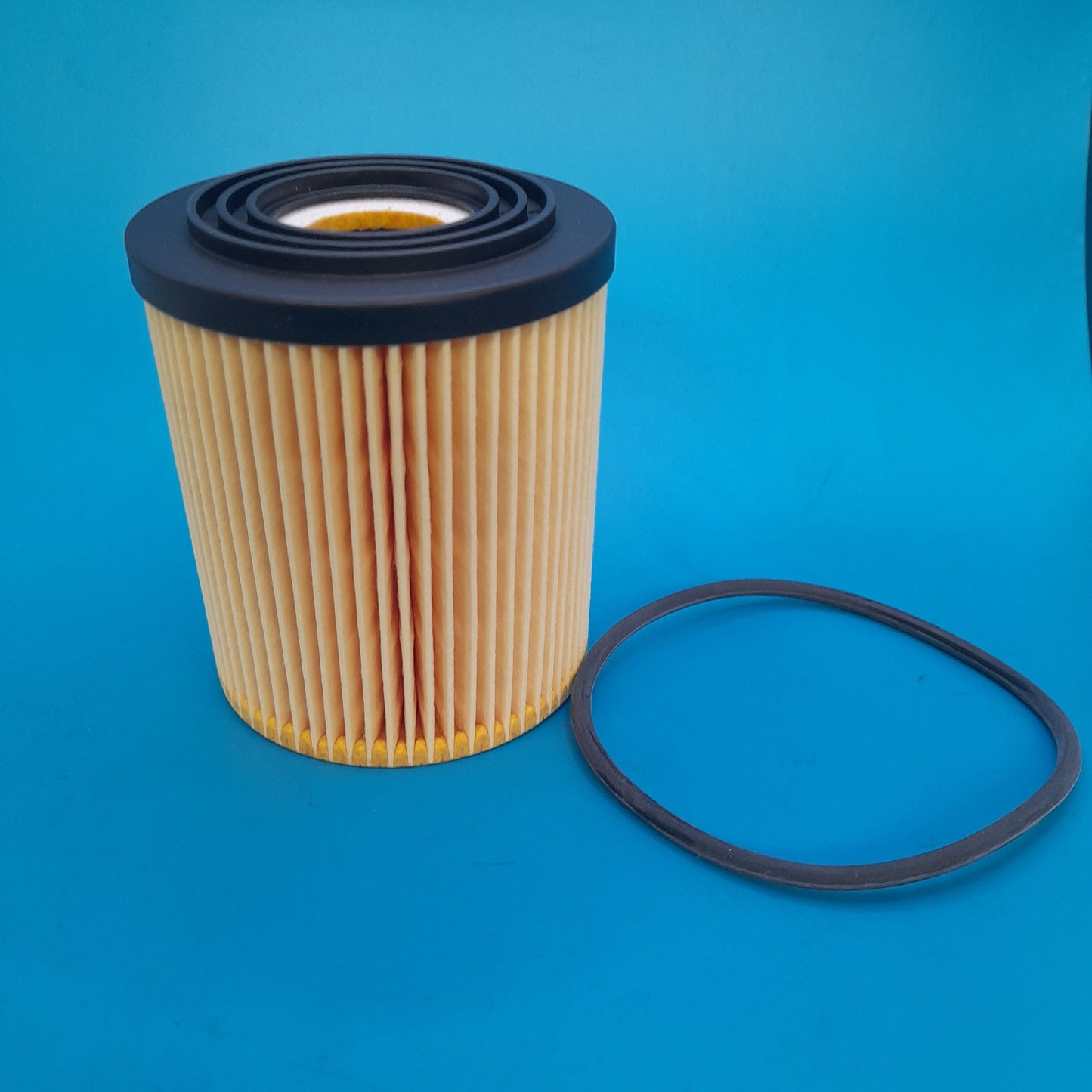 A Gen 1 Min cooper oil filter with a black top and a pleated filter media, displayed against a blue background.