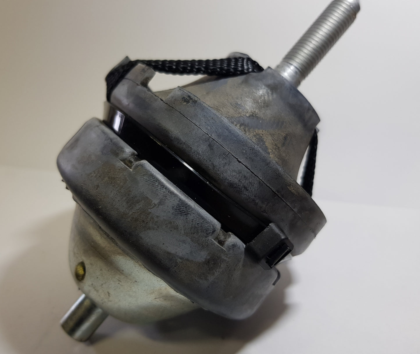 A top engine mount for a vehicle, appearing metallic with signs of wear and a securing knob on top.