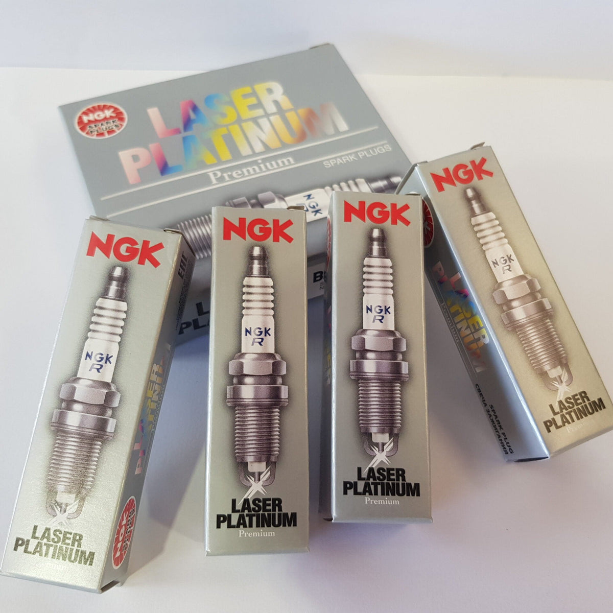 A set of NGK Laser Platinum sparkplugs in packaging, with the sparkplugs visible through a clear plastic window on the boxes.