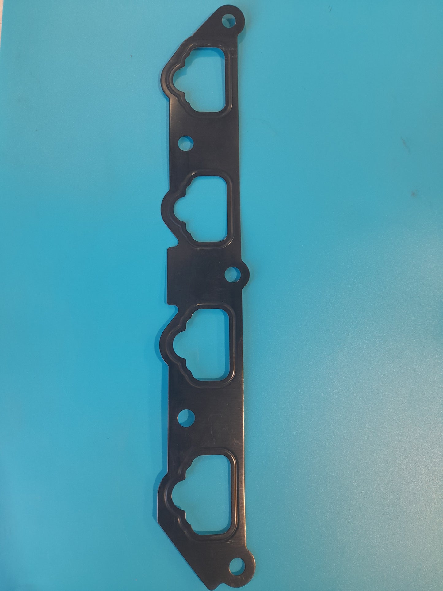 A Mini Cooper s inlet manifold gasket, with a blue background, designed for R52 and R53 Mini Cooper S models.