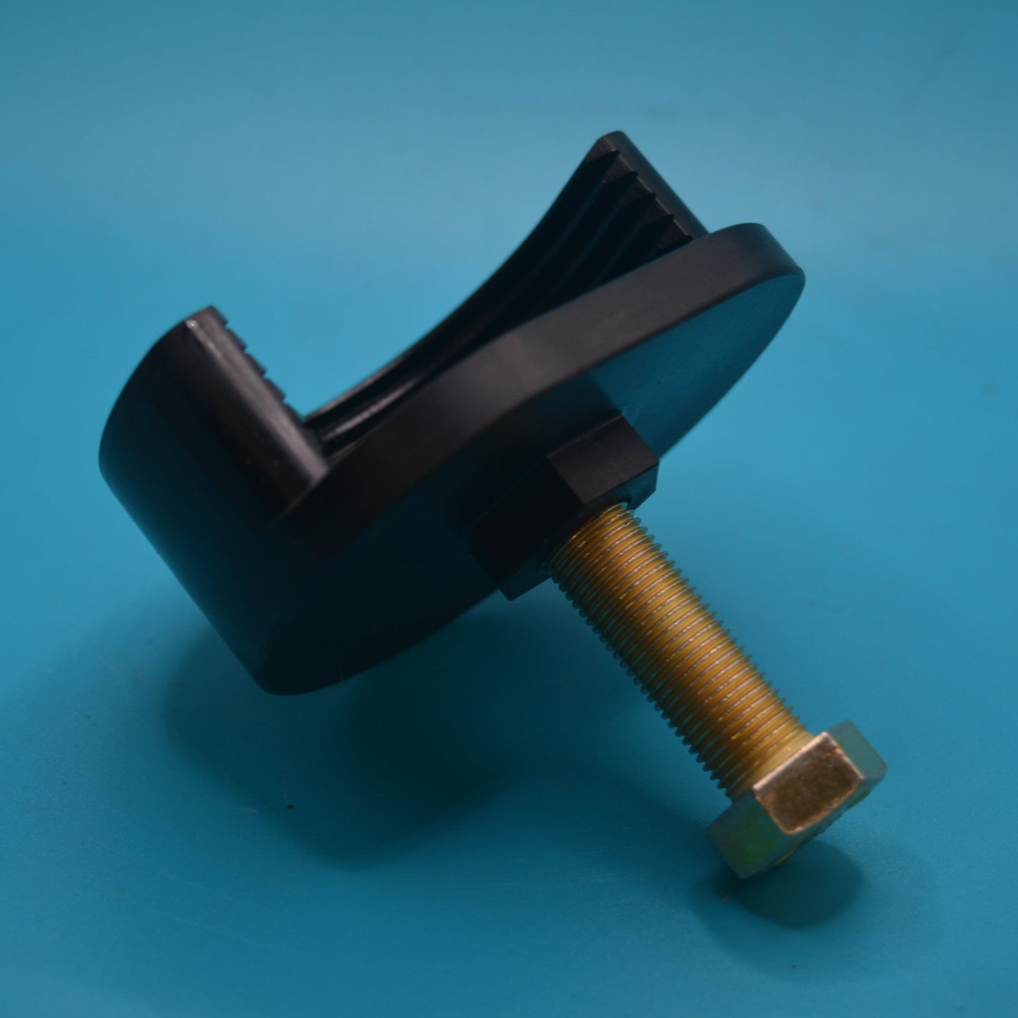 A black and gold metal pulley removal tool with a golden nut and a wrench-like handle, placed on a blue surface.