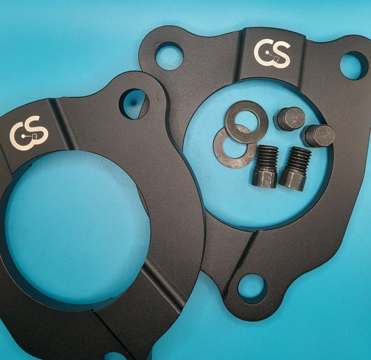 A pair of black strut tower defenders with accompanying bolts for mini cooper models