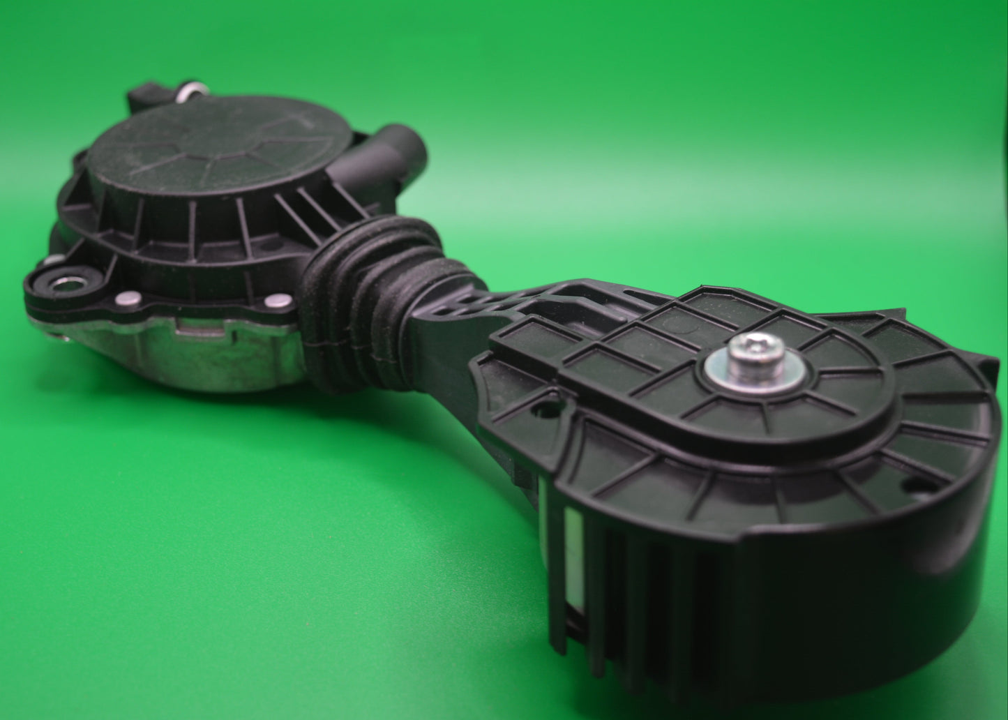 A black friction wheel for a drivebelt assembly, set against a green background.