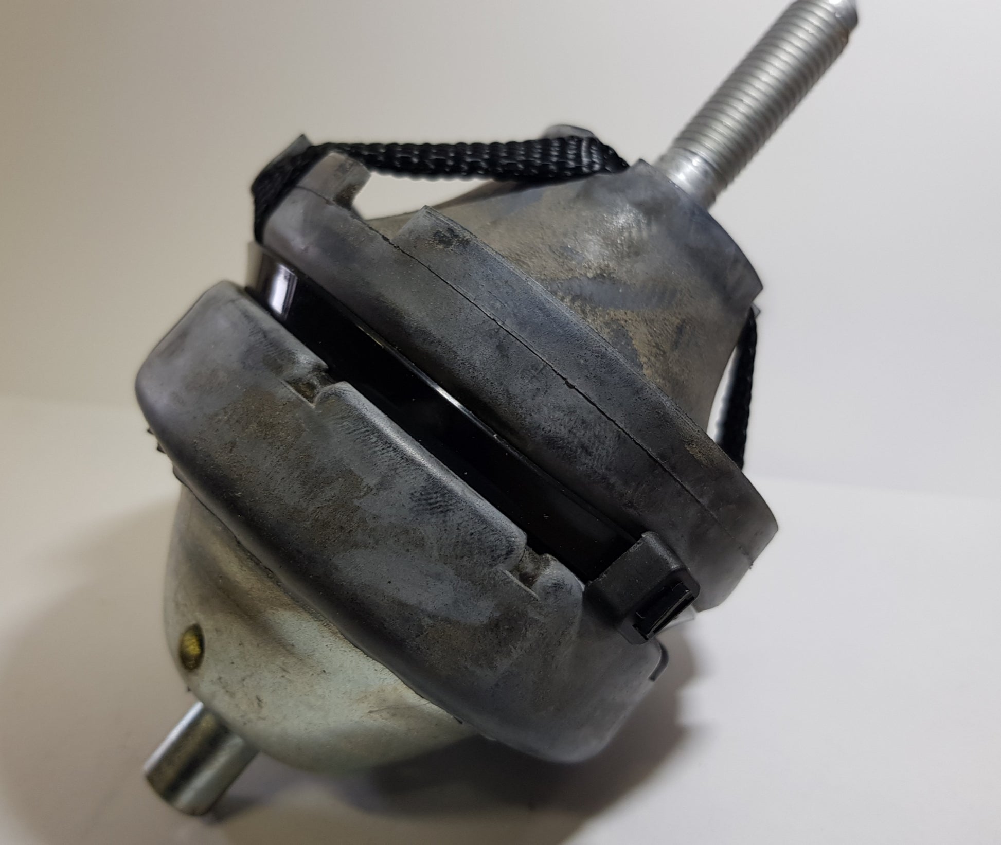 A top engine mount for a vehicle, appearing metallic with signs of wear and a securing knob on top.