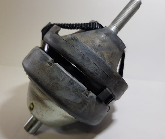 A top engine mount for a vehicle, appearing metallic with signs of wear and a securing knob on top.
