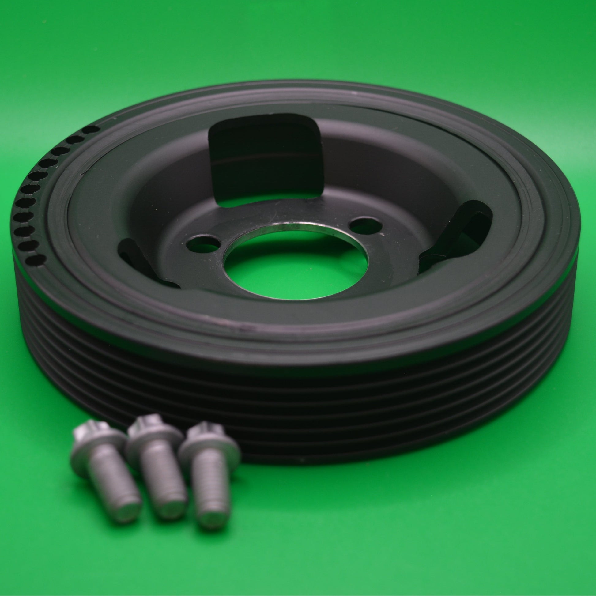 Harmonic balancer/crank shaft pulley for Mini Cooper models, displayed on a green background accompanied by installation bolts.