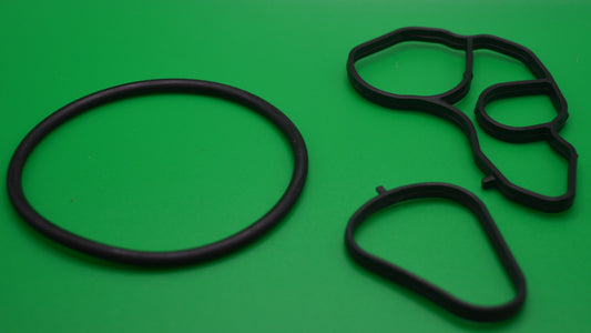 A set of black rubber gaskets and oil drain plugs on a green background.