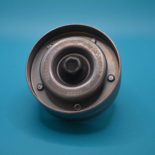 A Mini Cooper drive belt idler pulley, with a shiny metal finish, placed on a blue surface.