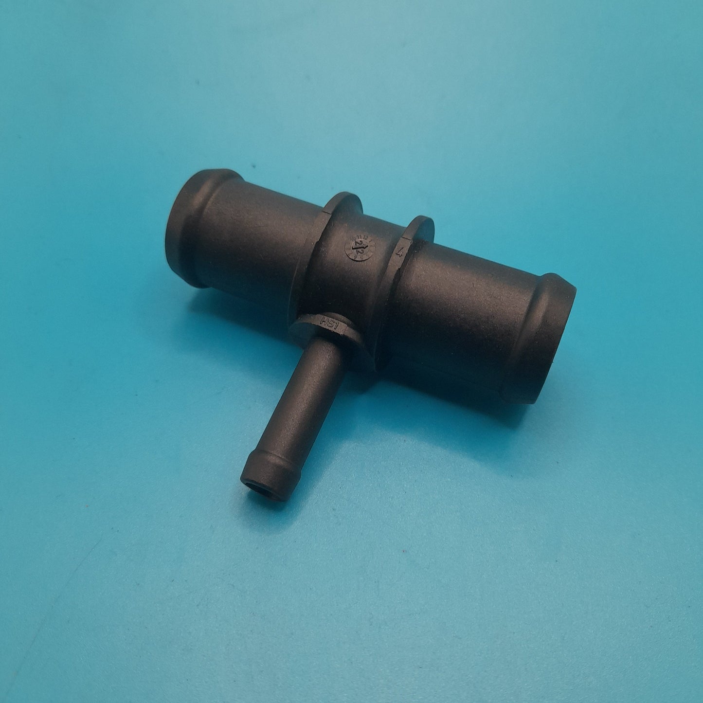 A black mini cooper heater to res bottle T-fitting positioned on a blue surface.