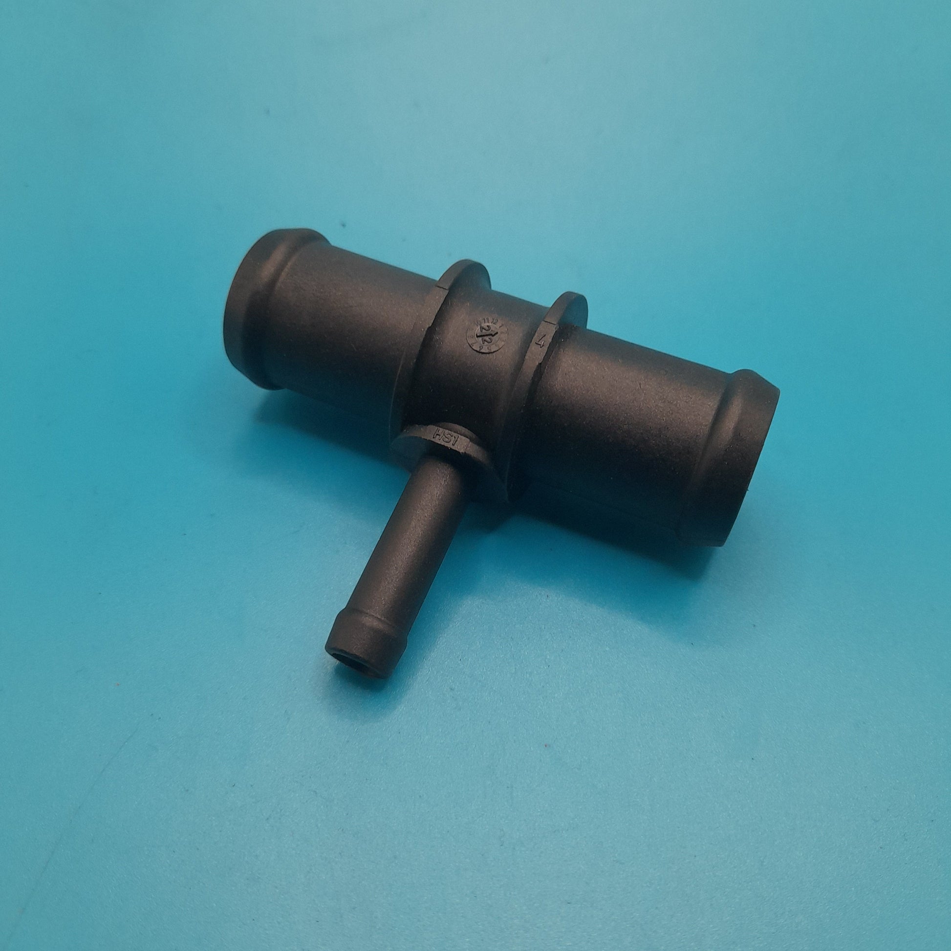 A black mini cooper heater to res bottle T-fitting positioned on a blue surface.