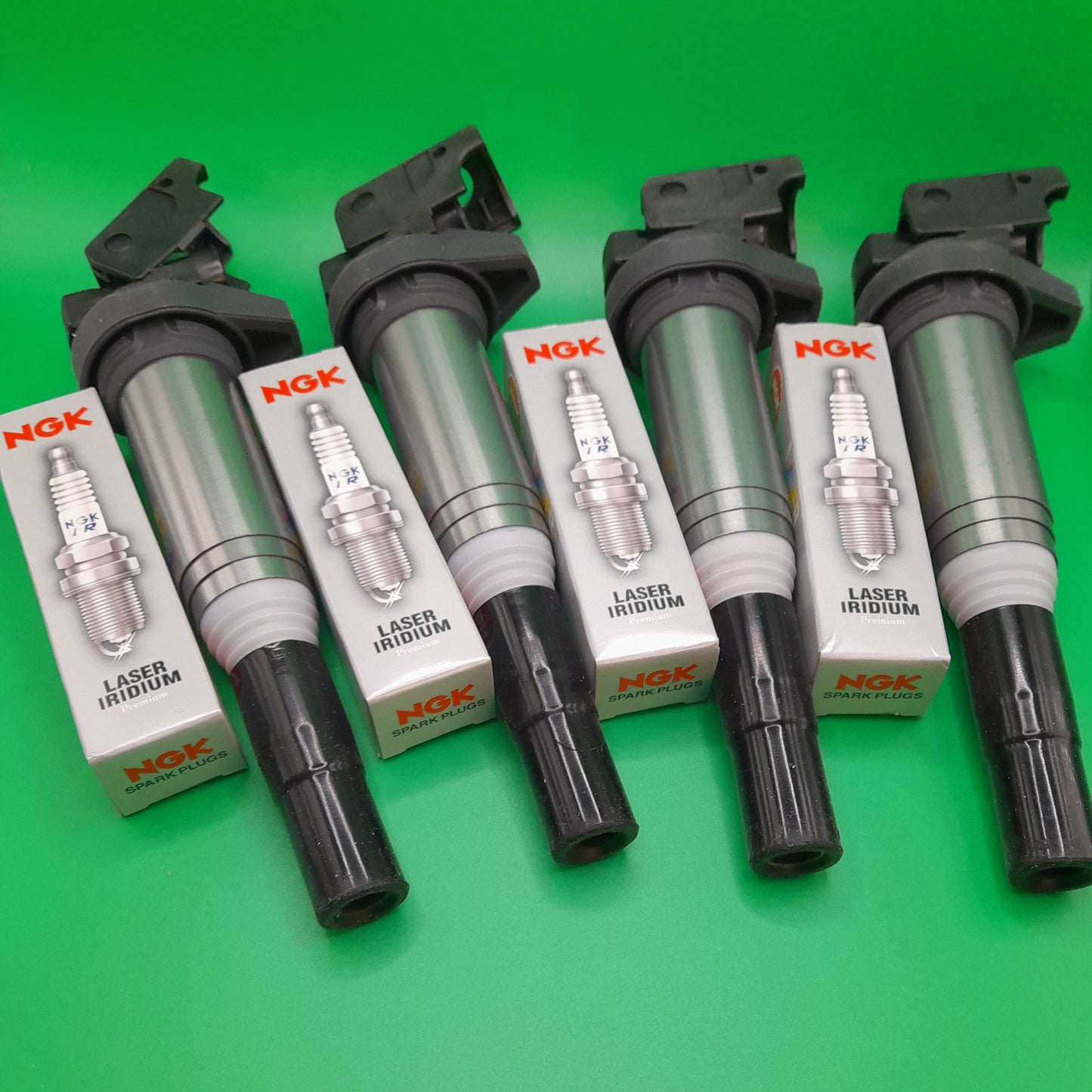 A set of four NGK spark plugs and coils for a mini cooper s n14
