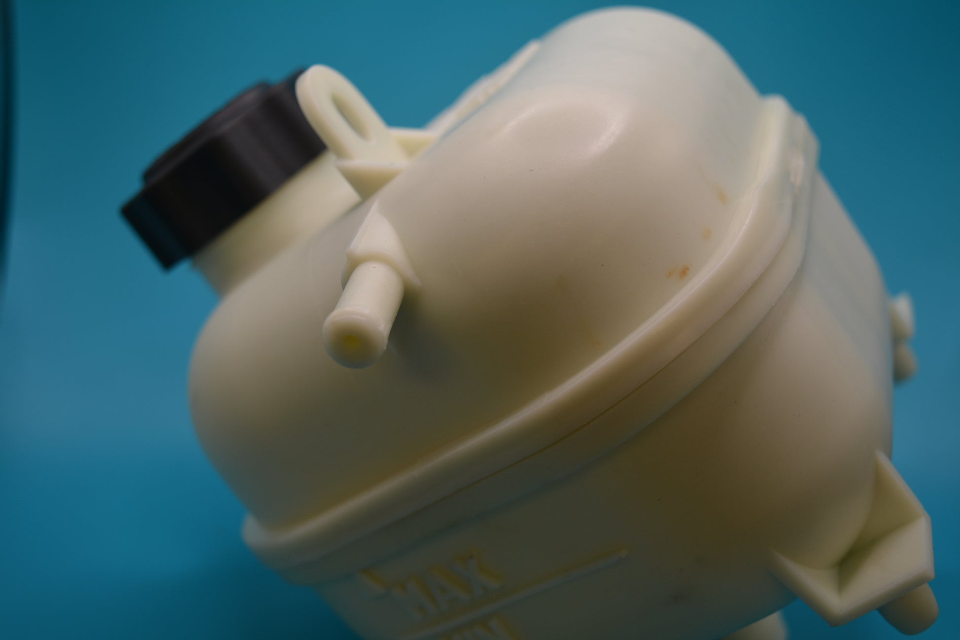 A beige-colored Mini Cooper S coolant bottle with a black cap.