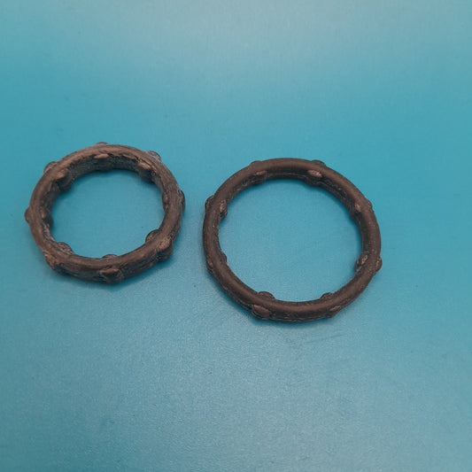 Two black oil pump seals placed on a blue surface.