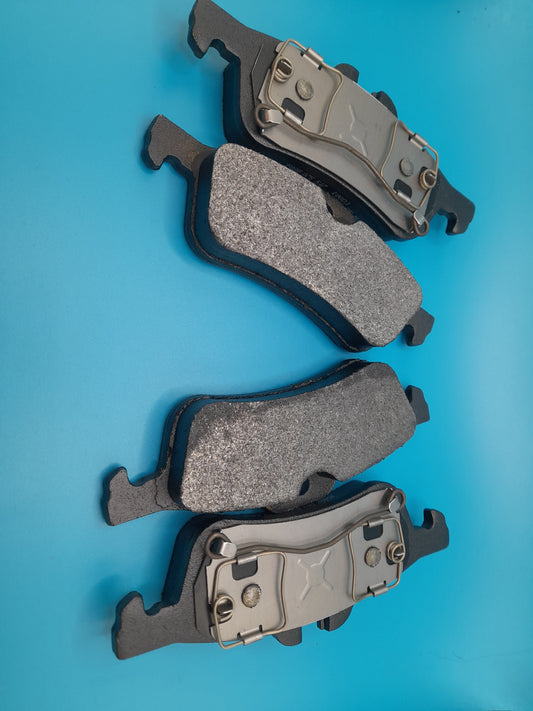 Set of four black Bosch quiet-cast brake pads arranged on a blue surface.