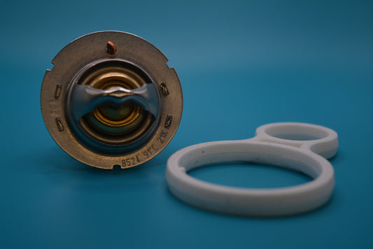 A single automotive thermostat with a gasket, isolated on a blue background
