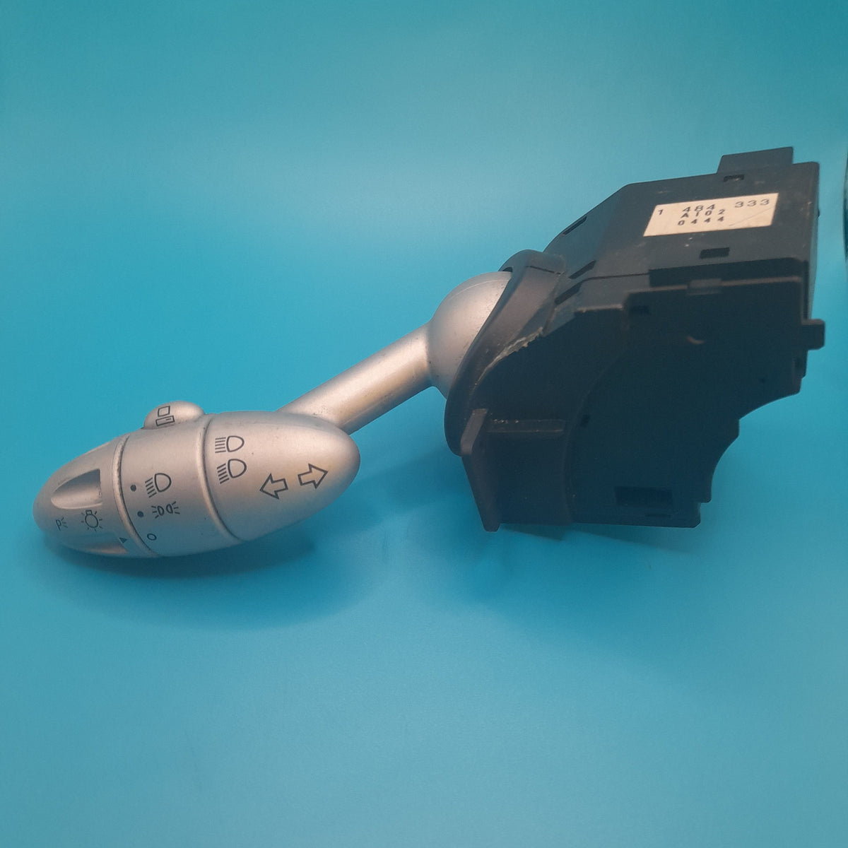 A Mini Cooper combination switch, featuring a stalk with control buttons for lighting and indicators, against a blue background.