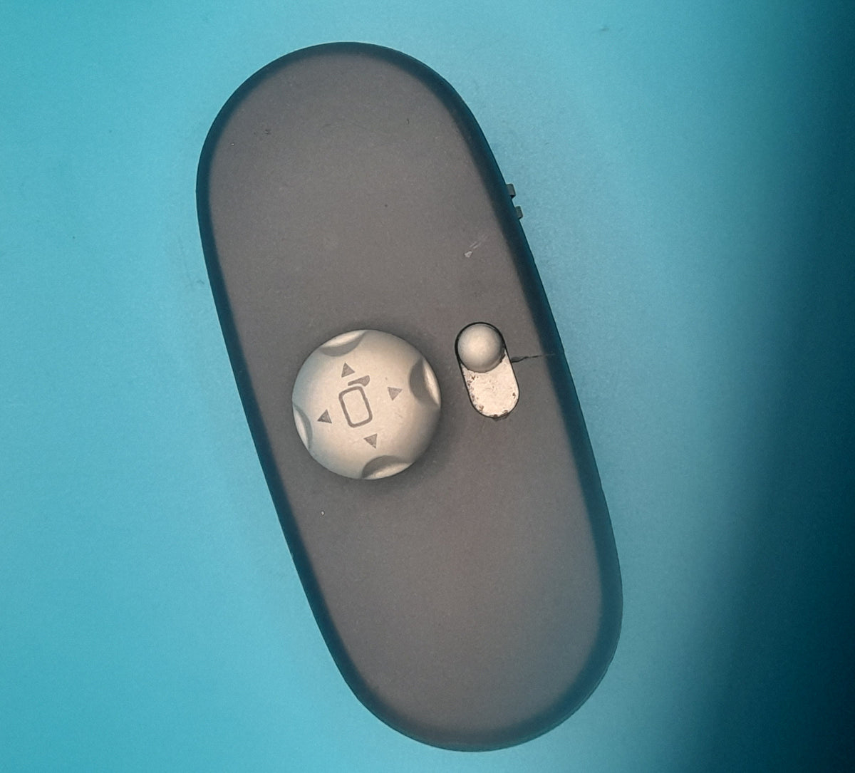 A black Mini Cooper side view mirror switch with visible signs of wear.